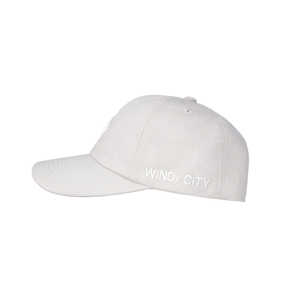 Left side of light gray cotton-nylon baseball cap, Windy City is embroidered in white capital letters on bottom edge